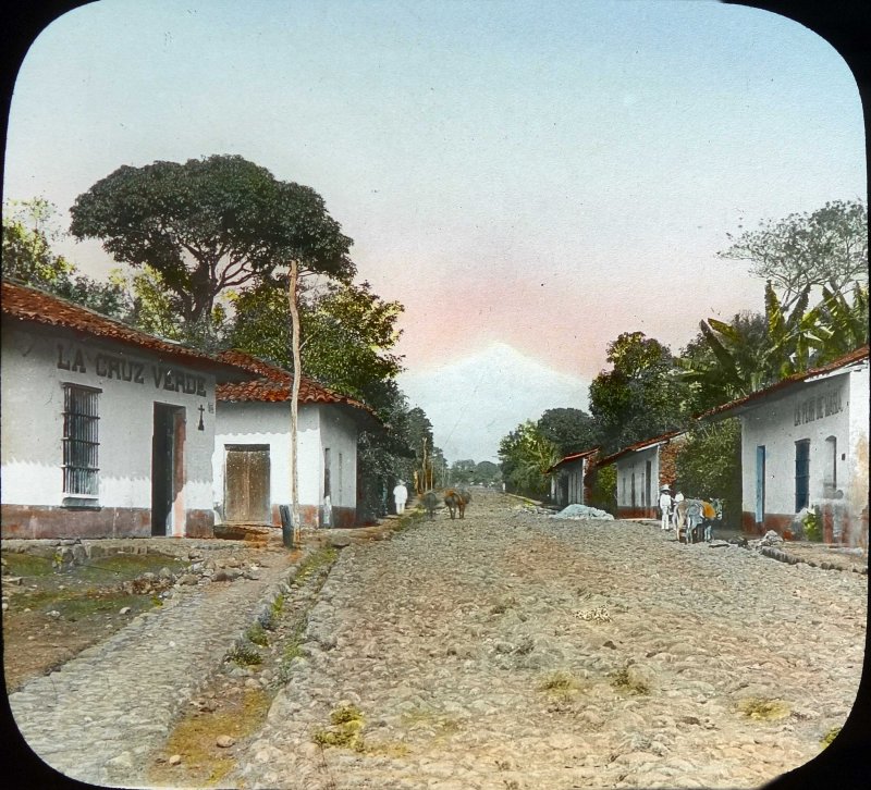 Escena callejera Tiendas de abarrotes La cruz verde y La flor de Mayo por el fotografo C B Waite 1906.